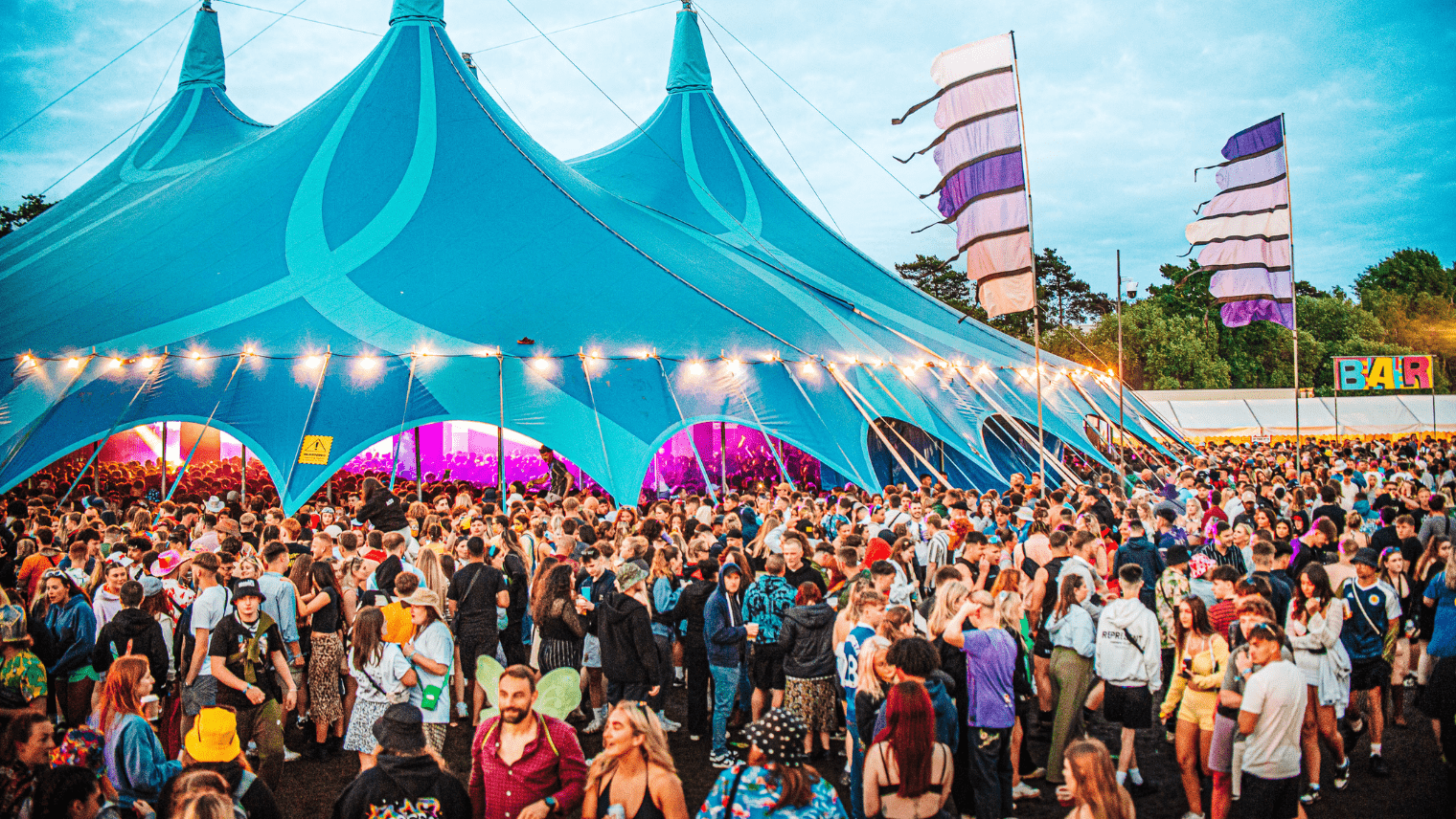 Festival tent with crowds of people in and around it