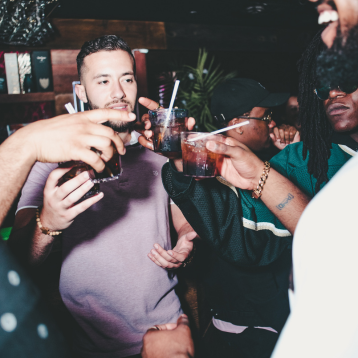  People doing a cheers at a bar with drinks