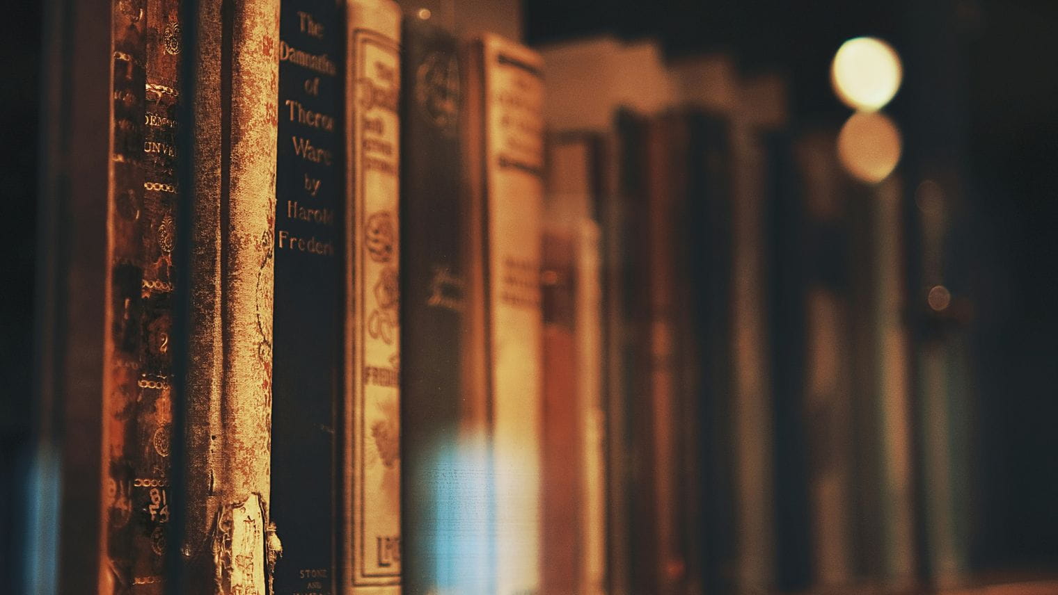 Old books leaning up against each other on a shelf