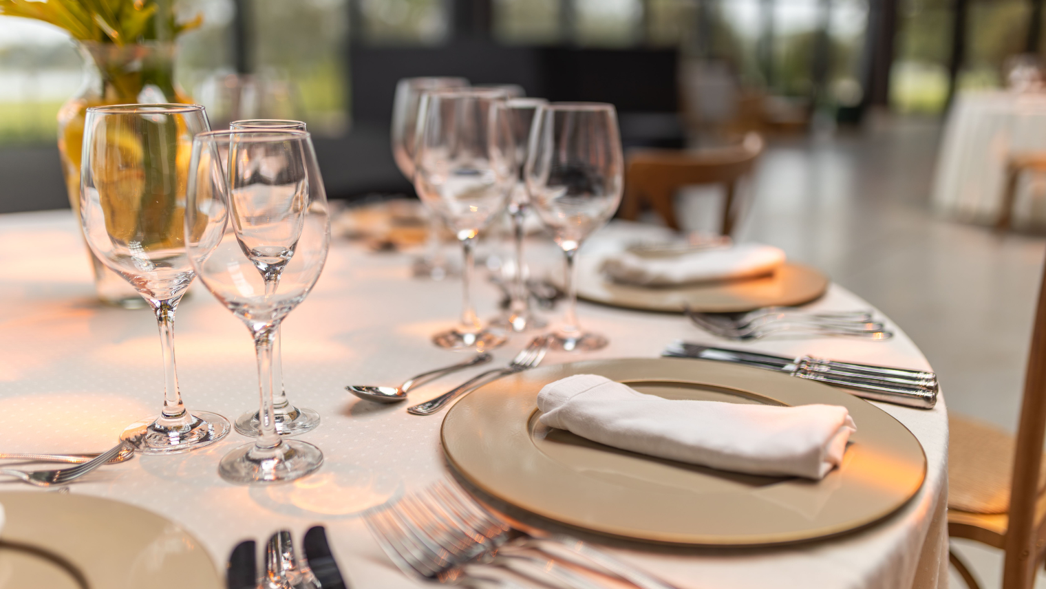 Formal table setting with gold plates, folded napkins, and glassware.