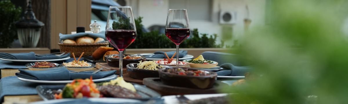 People dining with wine and salad at a restaurant table.