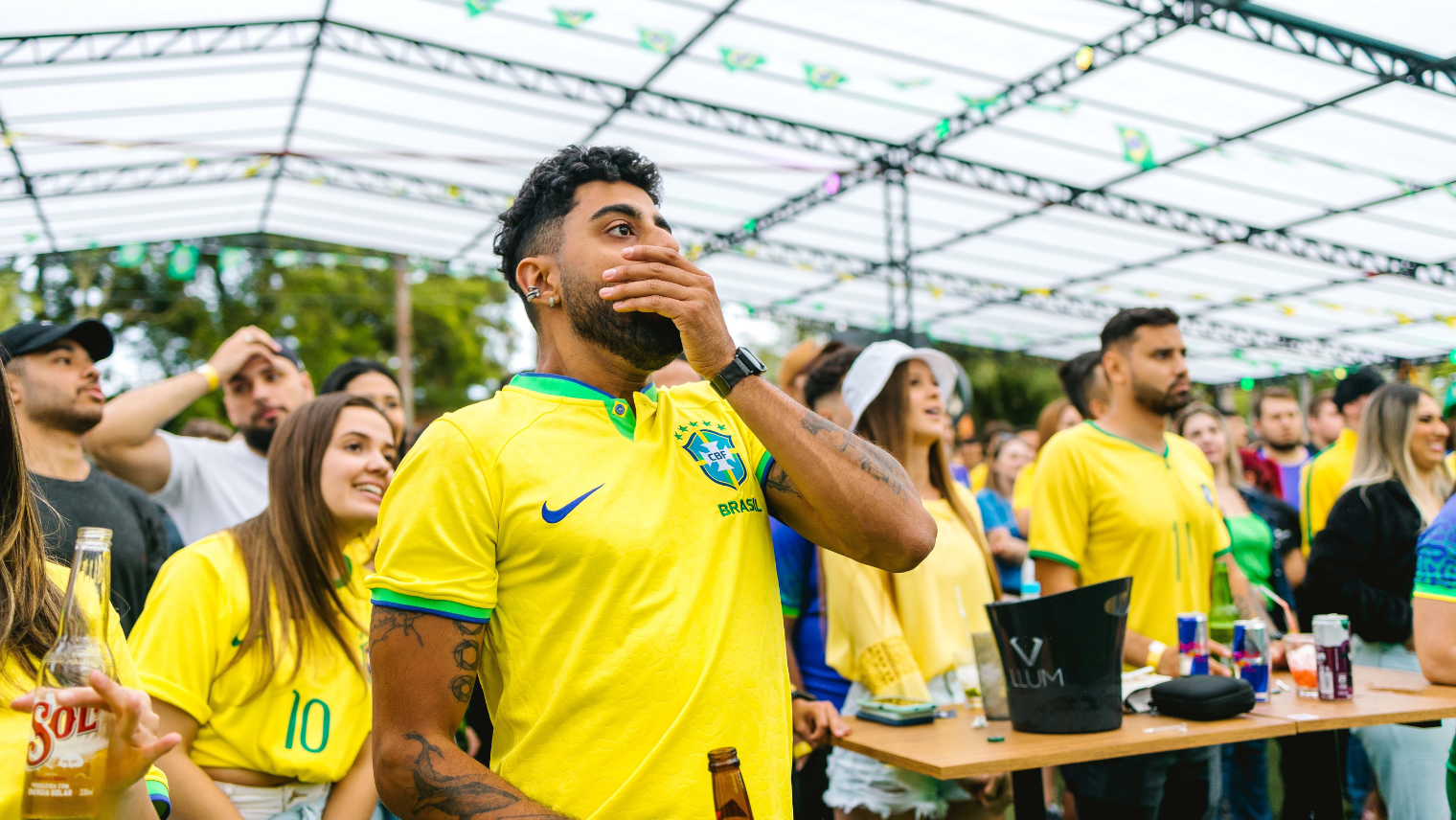Fans in Brazil jerseys reacting emotionally while watching a football match outdoors
